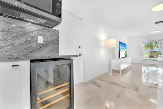 interior space featuring wine cooler, stainless steel microwave, visible vents, white cabinets, and light stone countertops