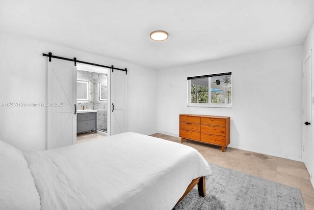 bedroom featuring a barn door, baseboards, and ensuite bathroom