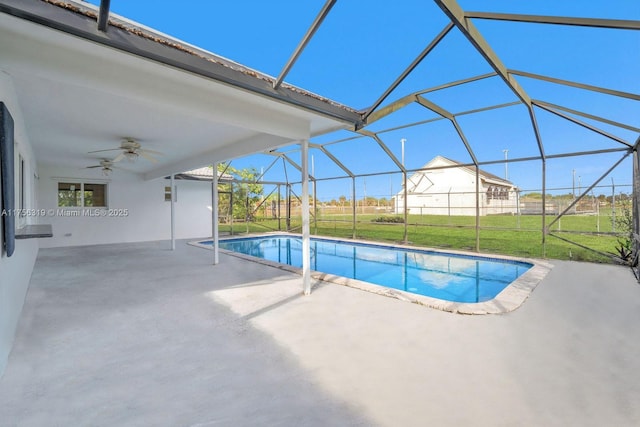 outdoor pool with ceiling fan, glass enclosure, a lawn, and a patio area