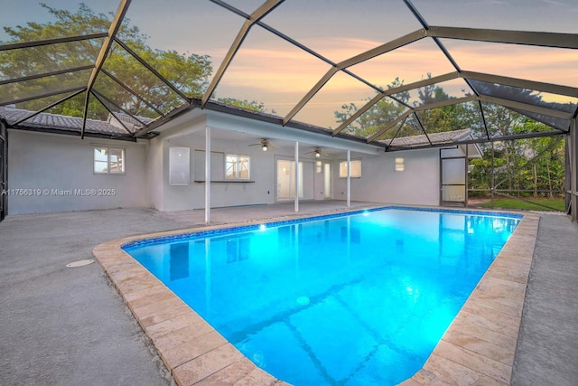 pool at dusk with a lanai, a patio area, ceiling fan, and an outdoor pool