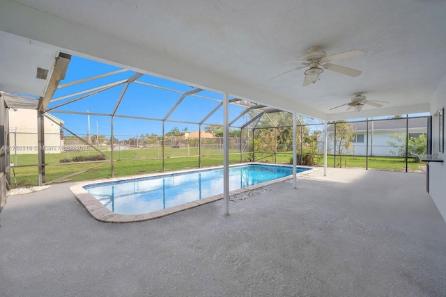 outdoor pool with ceiling fan, glass enclosure, a lawn, and a patio