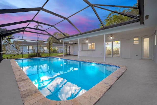 outdoor pool with ceiling fan, glass enclosure, and a patio area