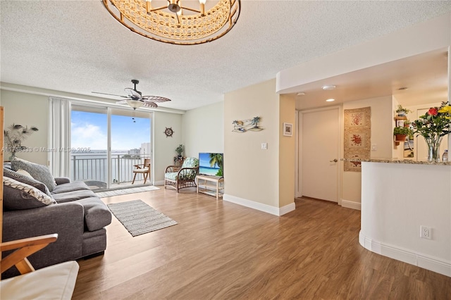 living area with a ceiling fan, baseboards, a textured ceiling, and light wood finished floors