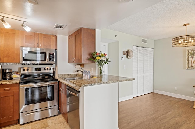 kitchen featuring appliances with stainless steel finishes, a sink, visible vents, and brown cabinets