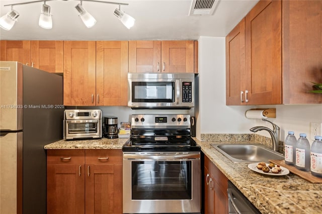 kitchen featuring a toaster, stainless steel appliances, visible vents, brown cabinetry, and a sink