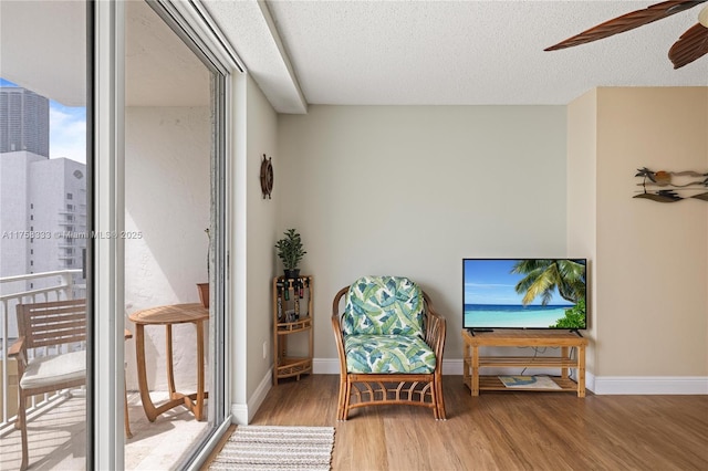 living area featuring a textured ceiling, baseboards, and wood finished floors