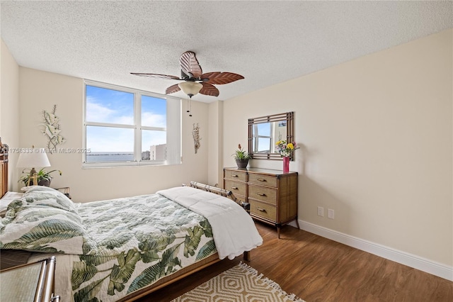 bedroom featuring multiple windows, a textured ceiling, baseboards, and wood finished floors