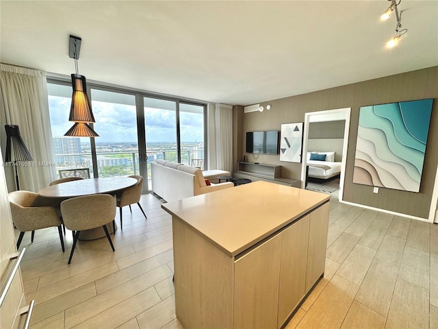 kitchen featuring pendant lighting, light countertops, wood tiled floor, a kitchen island, and a wall of windows