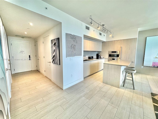 kitchen with light countertops, a breakfast bar, stainless steel oven, and wood tiled floor