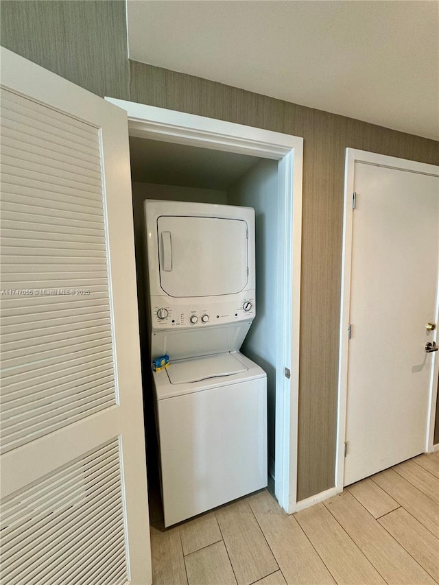 laundry room with stacked washer and dryer, laundry area, and wood finish floors