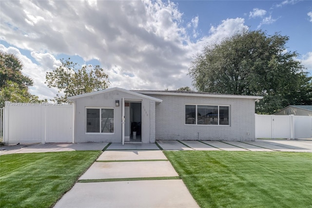 back of house featuring a yard, a patio area, brick siding, and fence