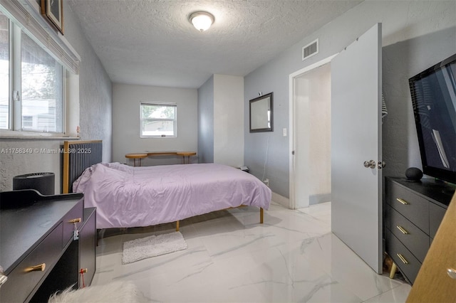 bedroom featuring marble finish floor, visible vents, and a textured ceiling