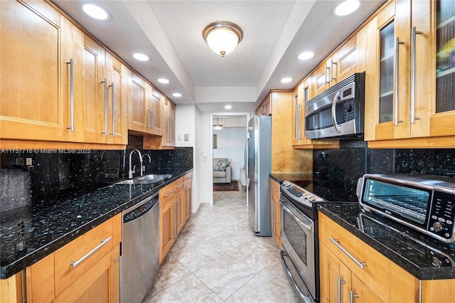 kitchen featuring a toaster, a sink, appliances with stainless steel finishes, tasteful backsplash, and a raised ceiling