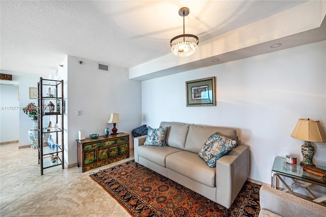 living area featuring baseboards, a notable chandelier, visible vents, and a textured ceiling