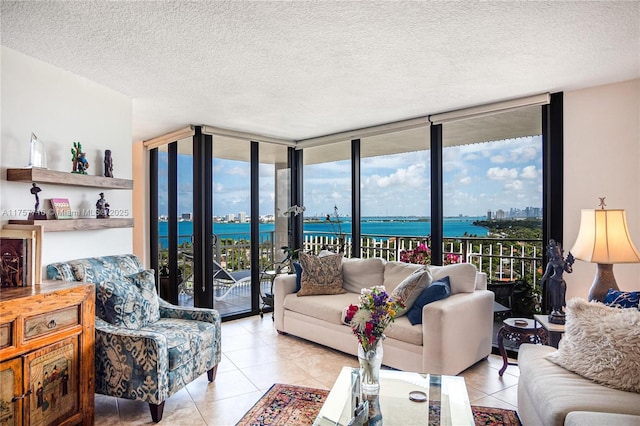 living area featuring light tile patterned floors, a wall of windows, a water view, and a textured ceiling