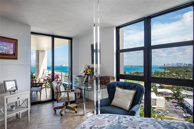 bedroom with a wall of windows, a water view, a textured ceiling, and tile patterned floors