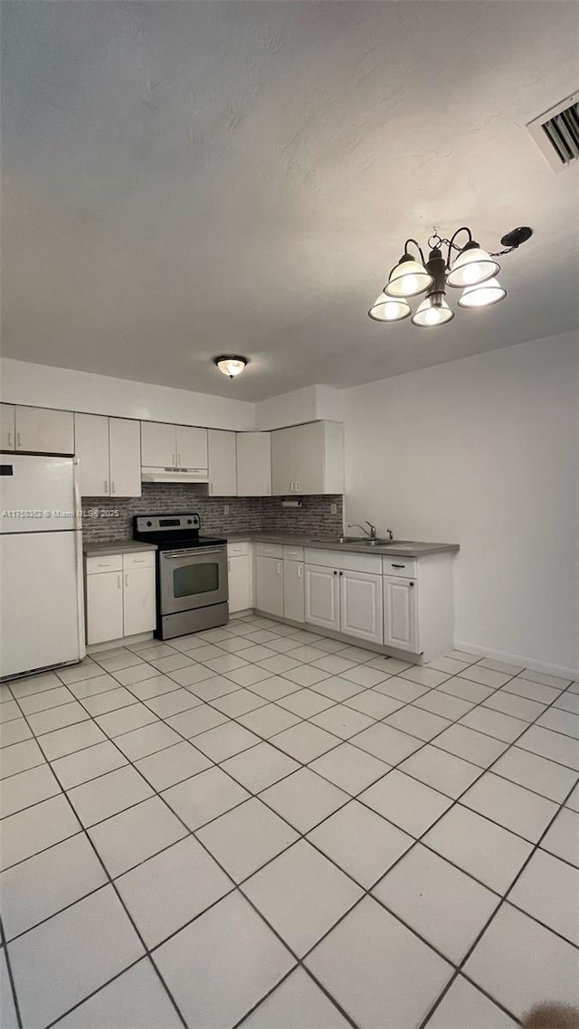 kitchen featuring under cabinet range hood, backsplash, freestanding refrigerator, and stainless steel electric stove