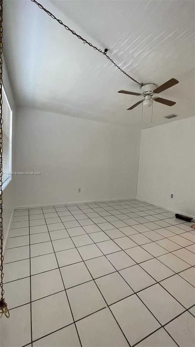 unfurnished room with ceiling fan, light tile patterned floors, visible vents, and baseboards