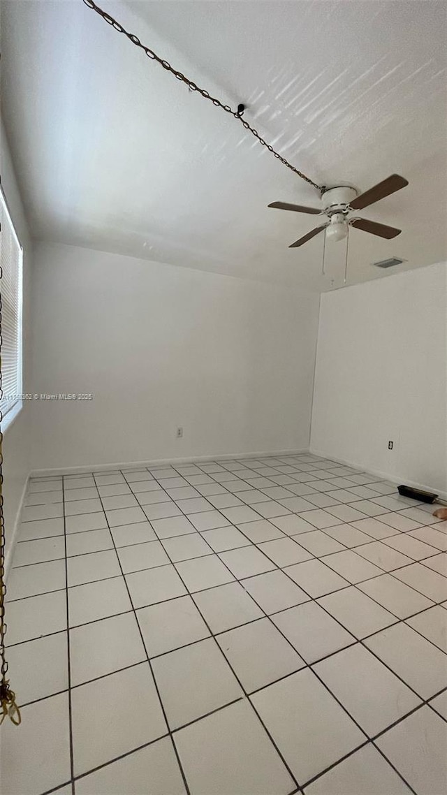 spare room with light tile patterned floors, visible vents, and a ceiling fan