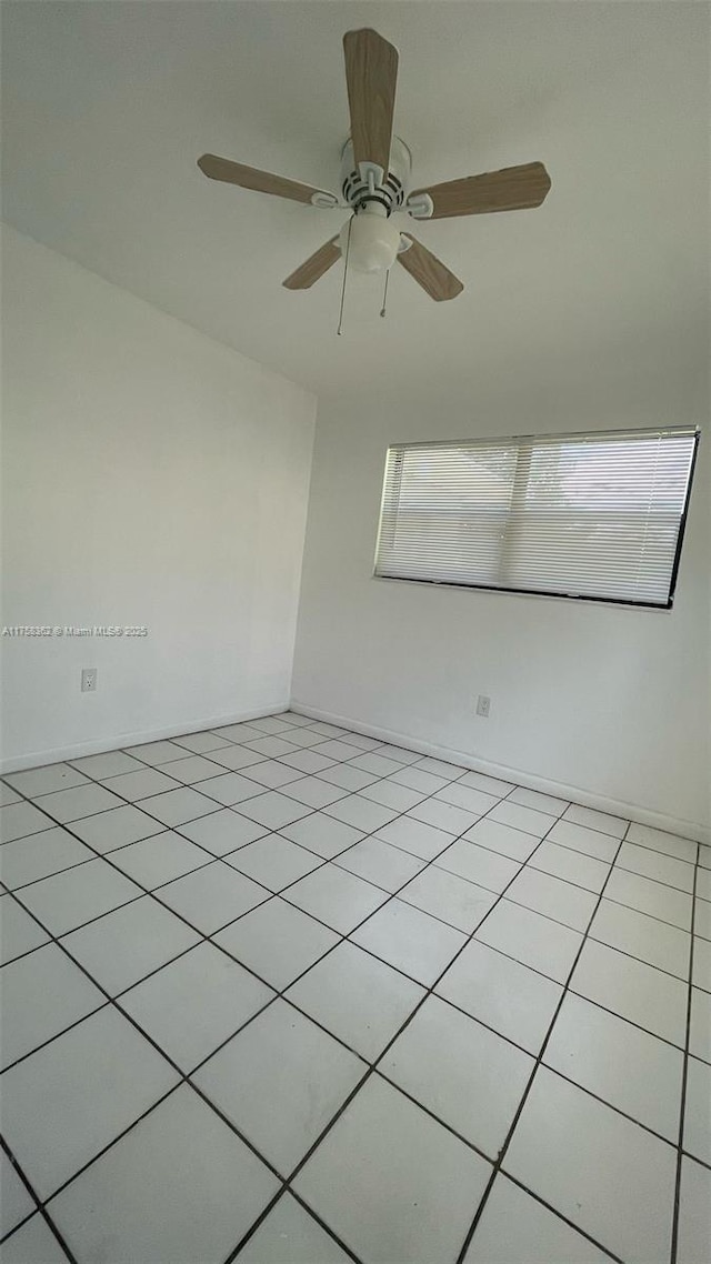 tiled empty room featuring a ceiling fan