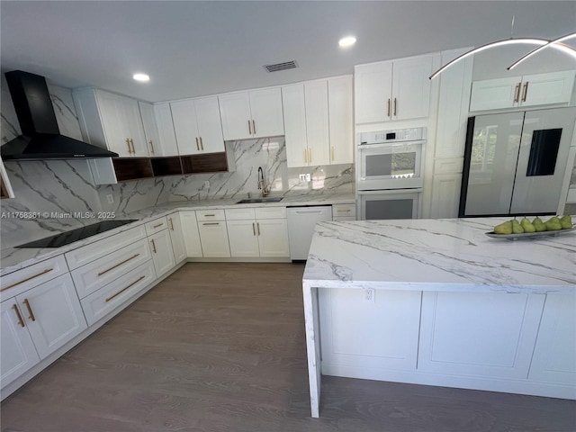 kitchen featuring white appliances, a sink, visible vents, wall chimney range hood, and tasteful backsplash