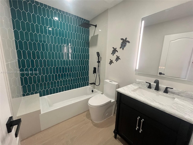 bathroom with tiled shower / bath, wood finished floors, vanity, and toilet