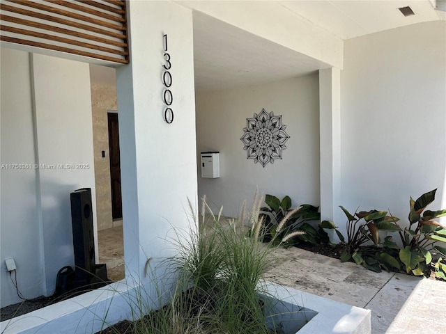 view of exterior entry with visible vents and stucco siding