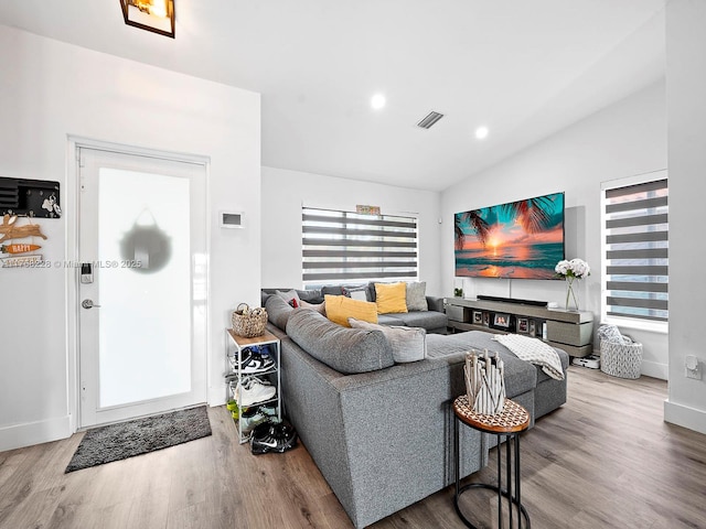 living room featuring vaulted ceiling, recessed lighting, wood finished floors, and visible vents