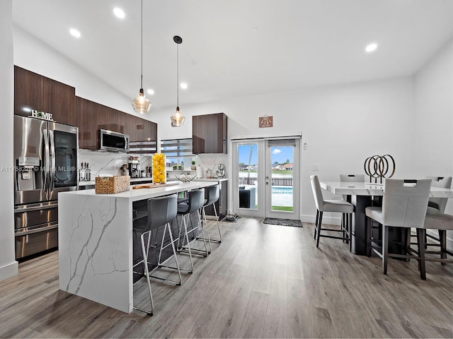 kitchen with a kitchen breakfast bar, dark brown cabinets, modern cabinets, and stainless steel appliances