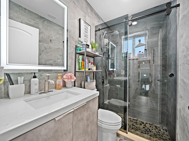 full bathroom featuring visible vents, a shower stall, tile walls, toilet, and vanity