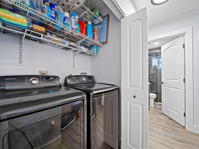 washroom with laundry area, separate washer and dryer, and light wood-type flooring