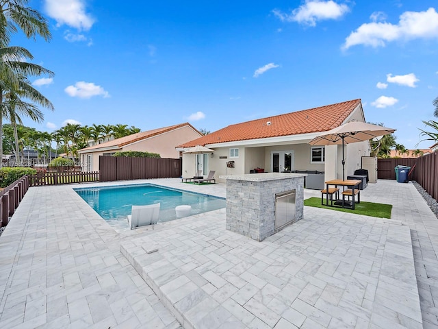 view of swimming pool with a patio area, a fenced in pool, a fenced backyard, and outdoor dry bar