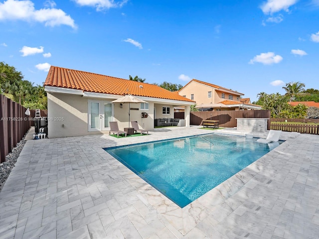 view of pool with a fenced in pool, a fenced backyard, french doors, outdoor lounge area, and a patio area