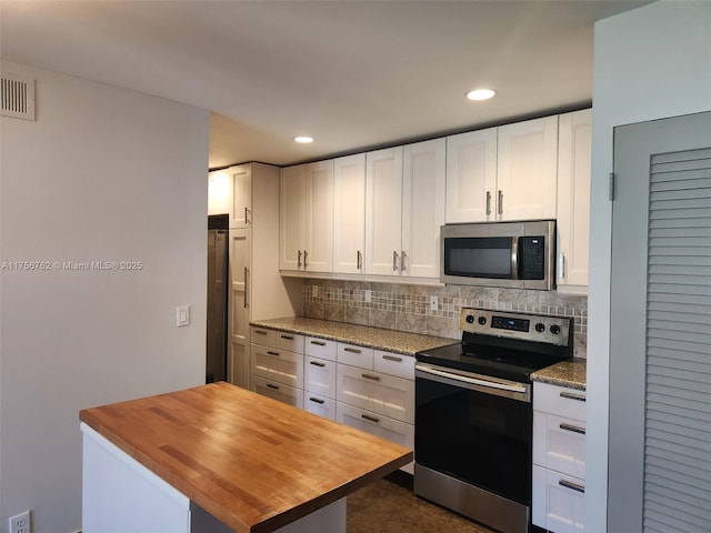 kitchen featuring stainless steel appliances, tasteful backsplash, wood counters, and visible vents