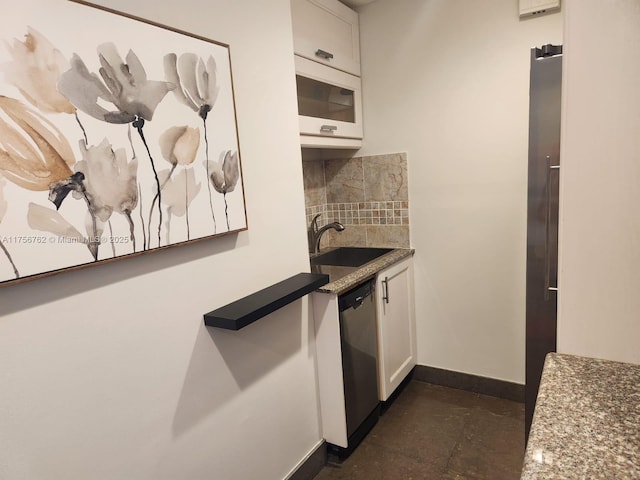 kitchen featuring tasteful backsplash, stainless steel dishwasher, white microwave, white cabinets, and a sink