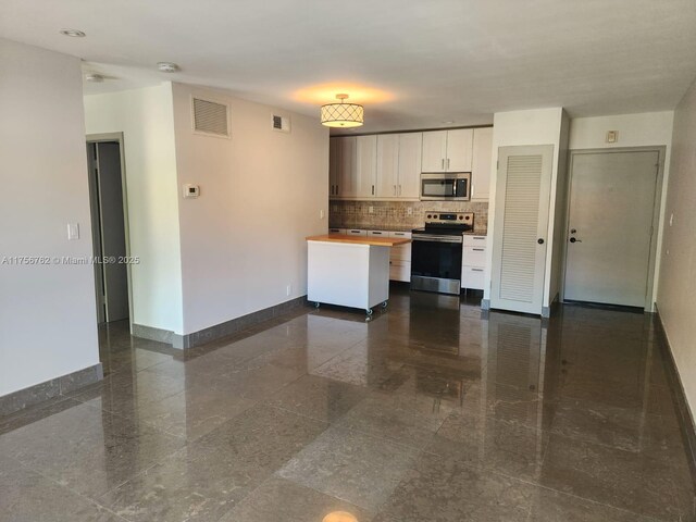 kitchen featuring granite finish floor, white cabinetry, visible vents, baseboards, and appliances with stainless steel finishes