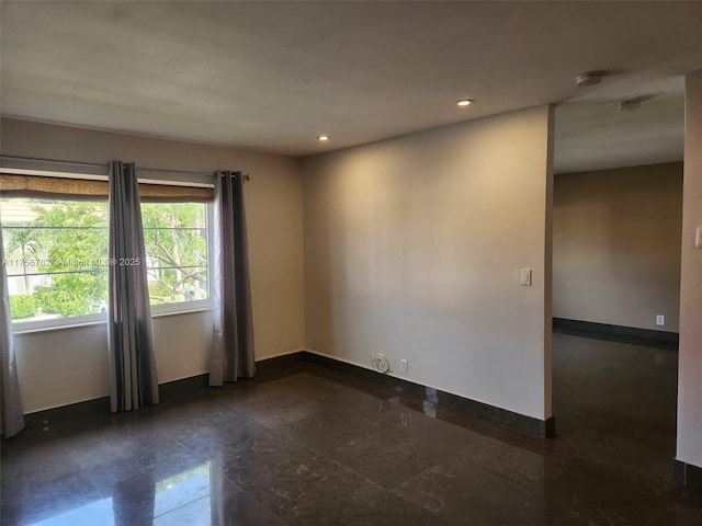 spare room featuring recessed lighting and baseboards