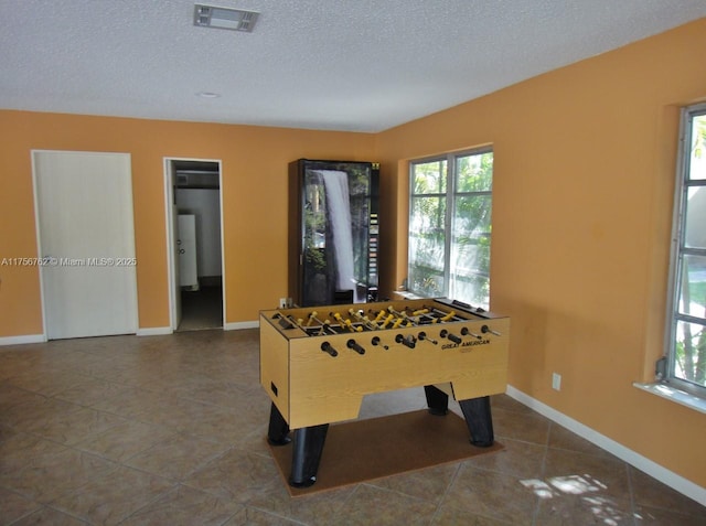 rec room featuring tile patterned flooring, visible vents, a textured ceiling, and baseboards