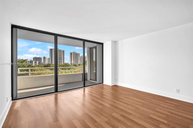 spare room featuring baseboards, a city view, and wood finished floors