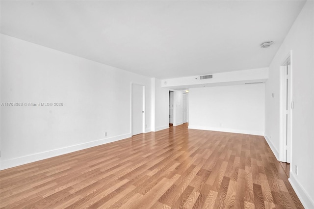 empty room featuring light wood finished floors, visible vents, and baseboards