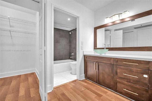 full bath featuring toilet, shower / washtub combination, wood finished floors, and vanity