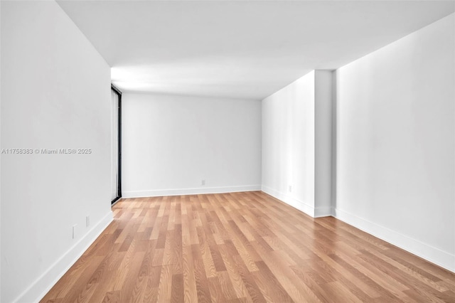 unfurnished room with light wood-type flooring and baseboards