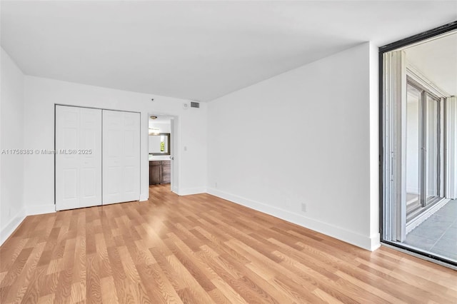 unfurnished bedroom featuring a closet, visible vents, light wood-style flooring, and baseboards