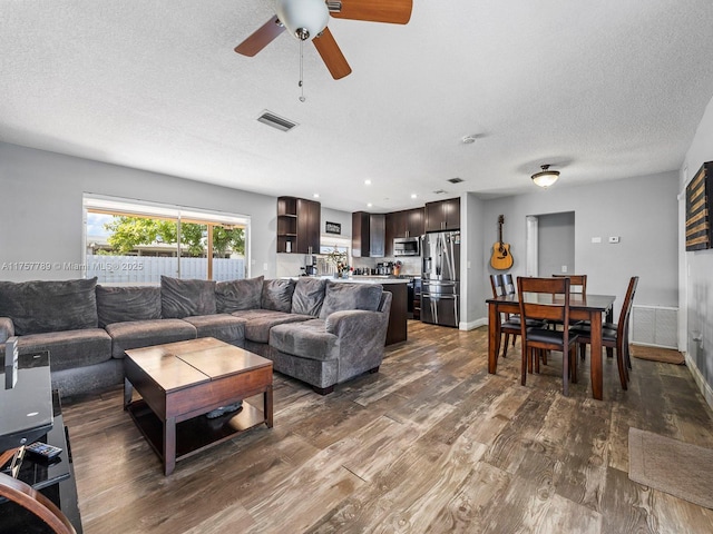 living room featuring dark wood-style floors, recessed lighting, visible vents, a textured ceiling, and baseboards