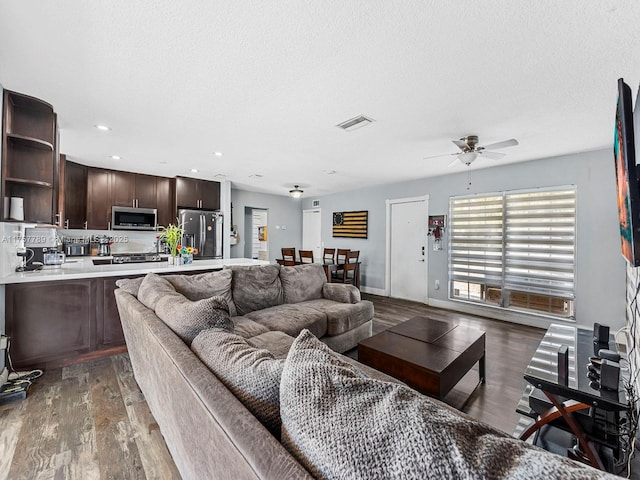 living room with a textured ceiling, dark wood finished floors, visible vents, and baseboards