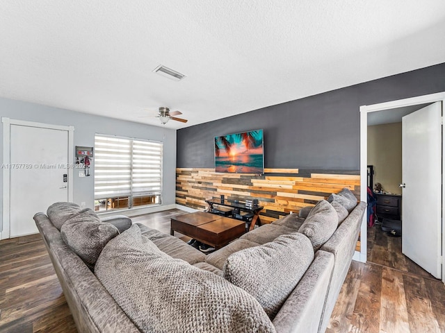 living room with a textured ceiling, wainscoting, wood finished floors, and visible vents