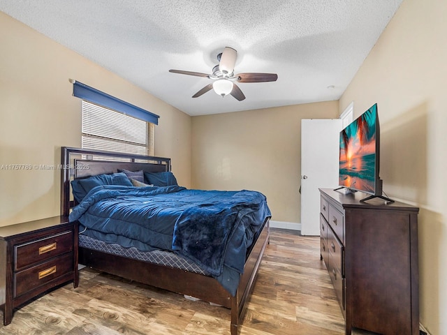 bedroom with a textured ceiling, ceiling fan, wood finished floors, and baseboards