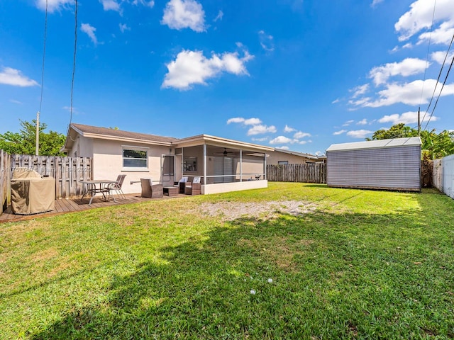 back of house featuring a fenced backyard, an outdoor structure, a sunroom, a lawn, and stucco siding