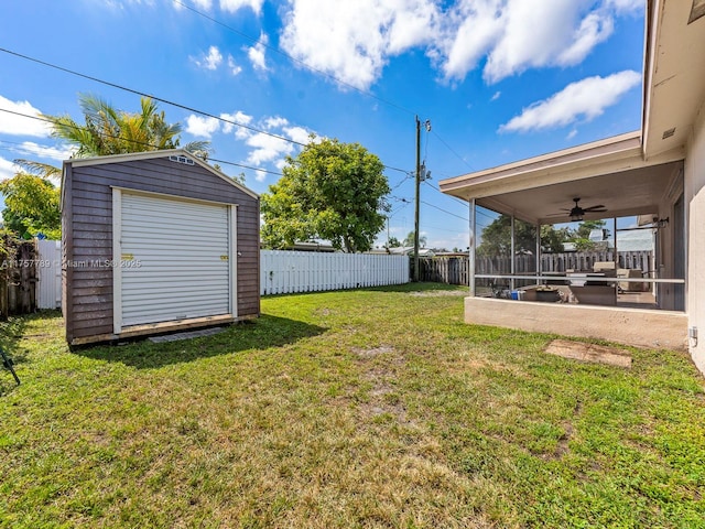 view of yard featuring a fenced backyard, a storage shed, an outdoor structure, a sunroom, and a ceiling fan