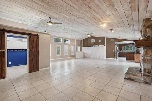 unfurnished living room featuring light tile patterned floors, a barn door, a ceiling fan, lofted ceiling, and wooden ceiling